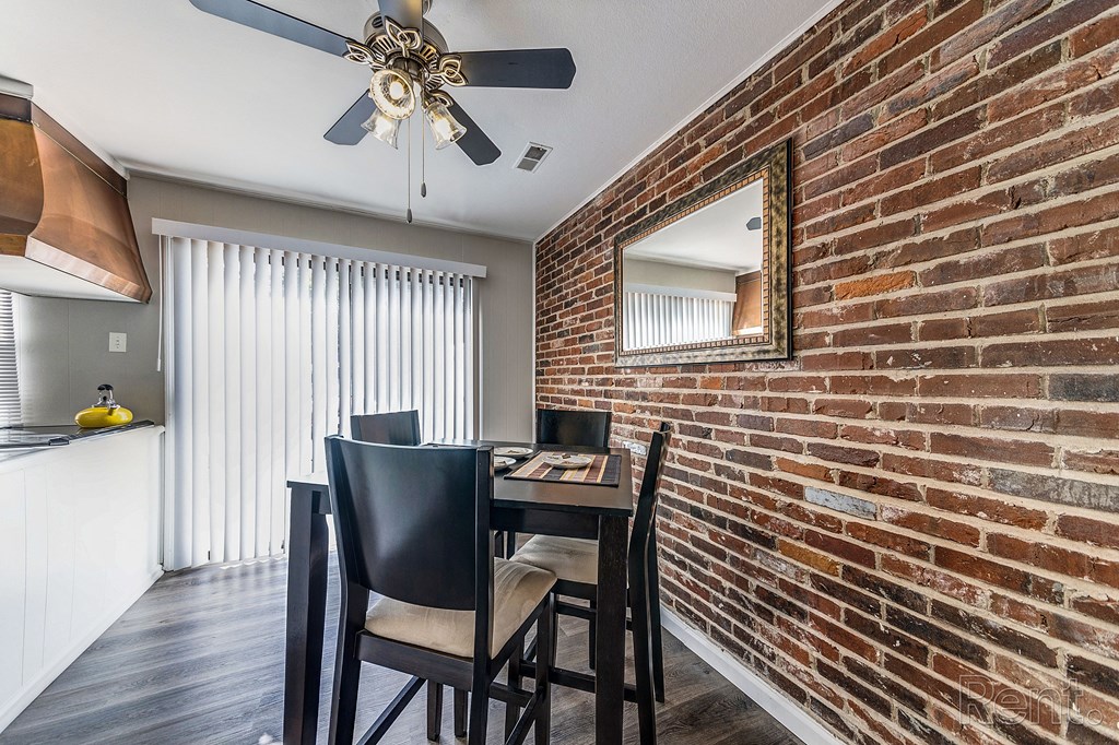 an exposed brick wall in a dining room with a table and chairs