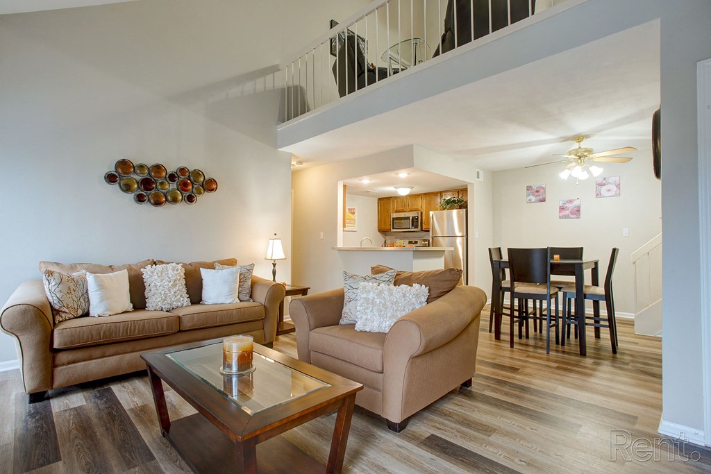 a living room with couches and a coffee table in front of a dining room