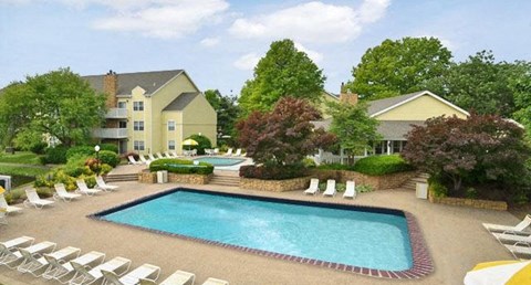a swimming pool with chairs and a building in the background