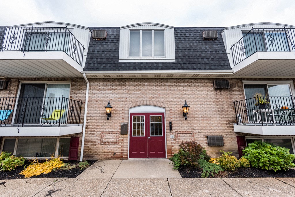 the front of a brick building with a red door