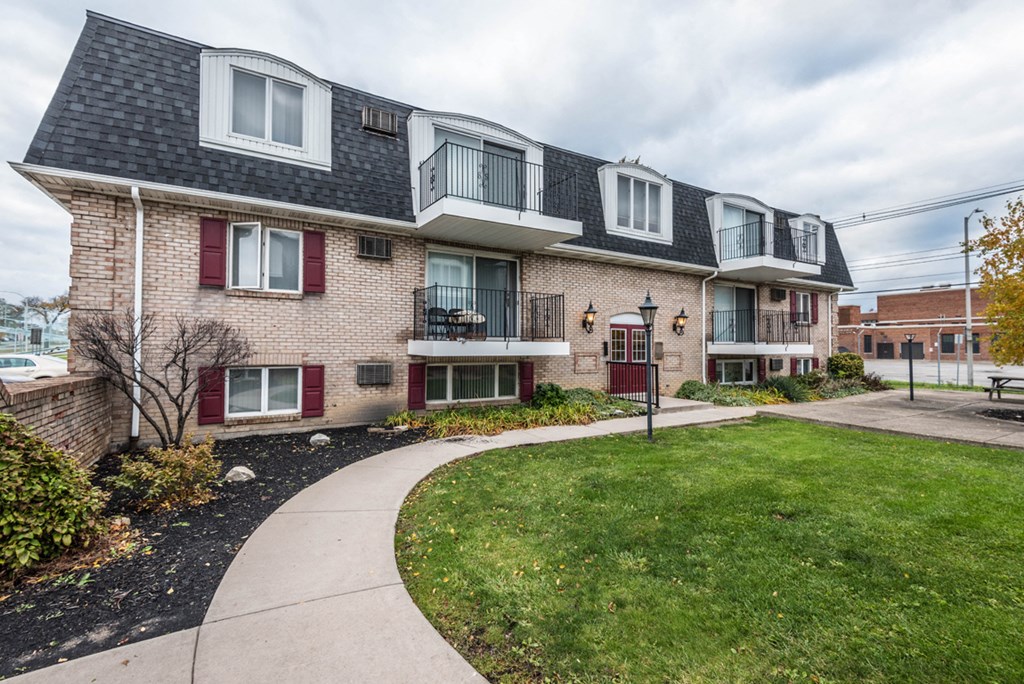 a brick apartment building with red doors and a sidewalk