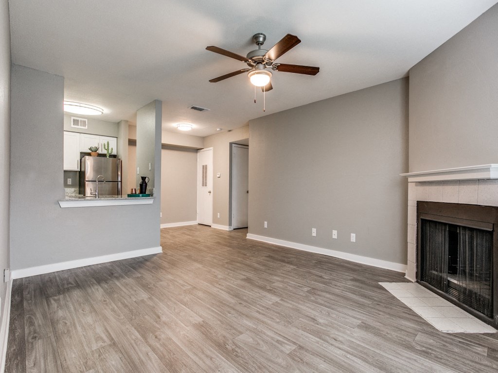 an empty living room with a fireplace and a ceiling fan