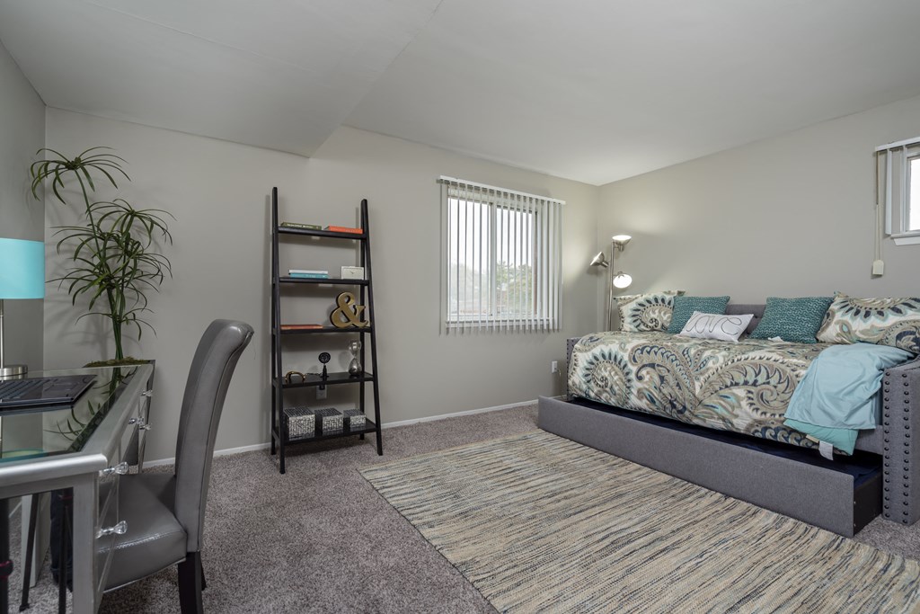 a bedroom with a bed and a desk and a window