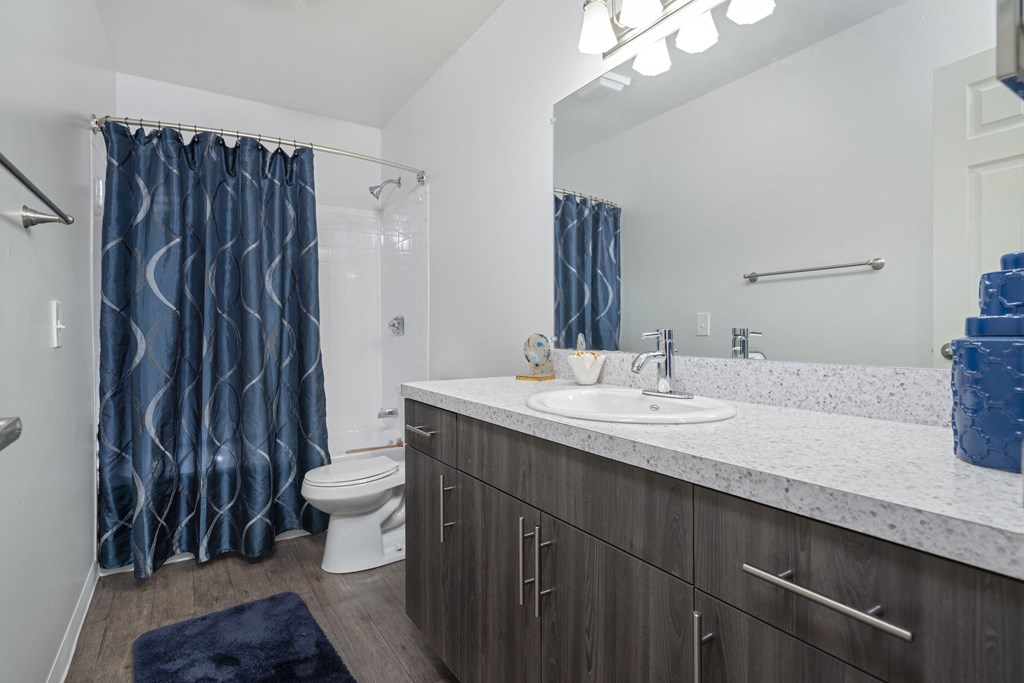 a bathroom with a sink toilet and shower and a blue shower curtain