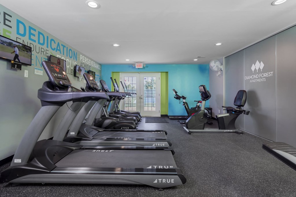 a gym with treadmills and other exercise equipment in a room with a door