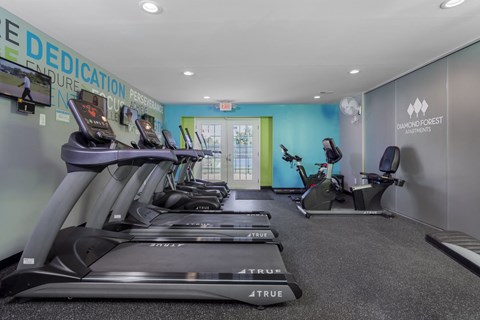 a gym with treadmills and other exercise equipment in a room with a door
