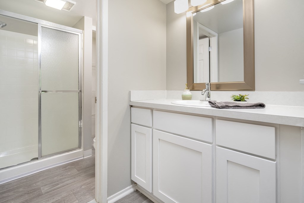 a bathroom with white cabinets and a shower and a sink