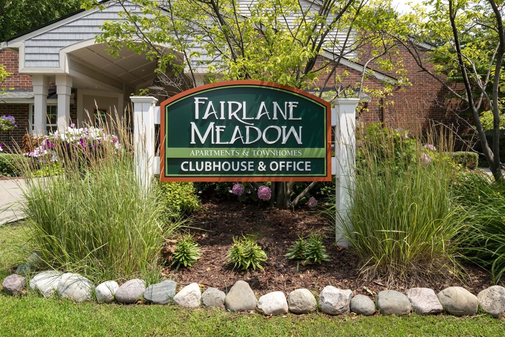 a sign for the fairlane meadow clubhouse and office in front of a house