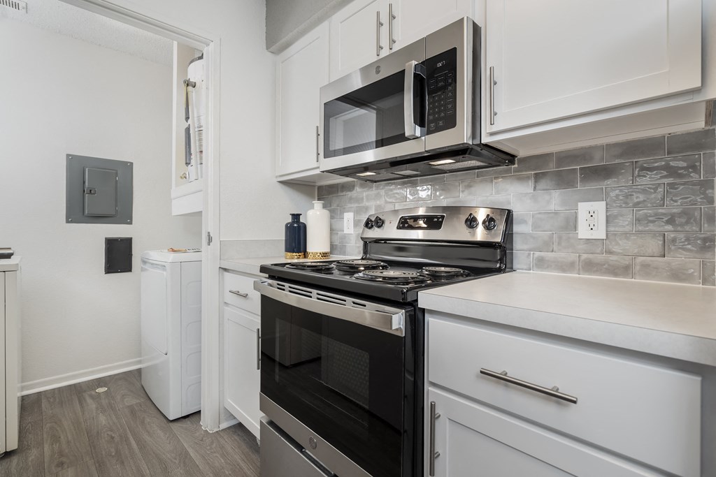 a kitchen with white cabinets and black appliances and a microwave