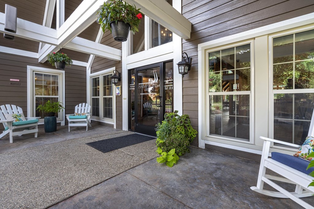 the front porch of a house with rocking chairs and a door