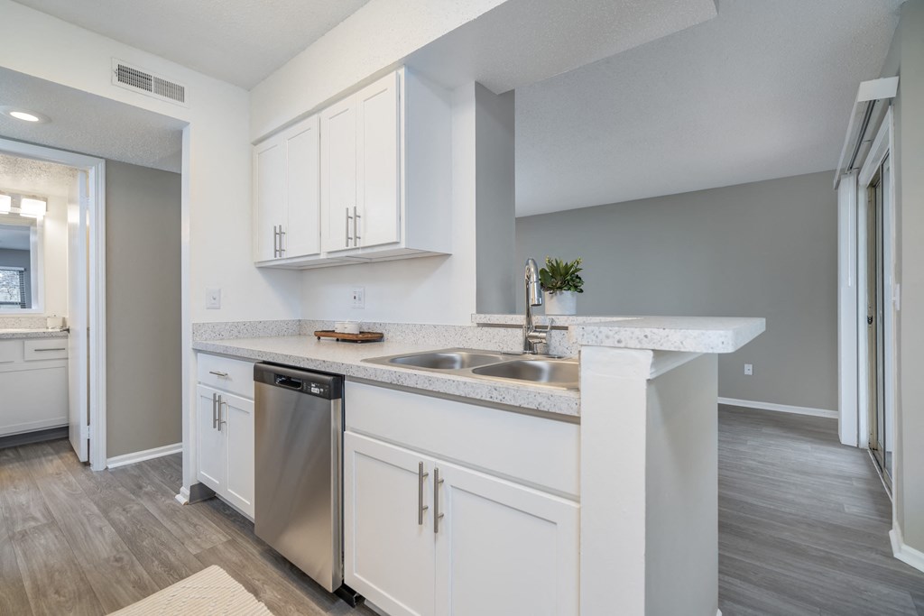 an empty kitchen with white cabinets and a stainless steel sink