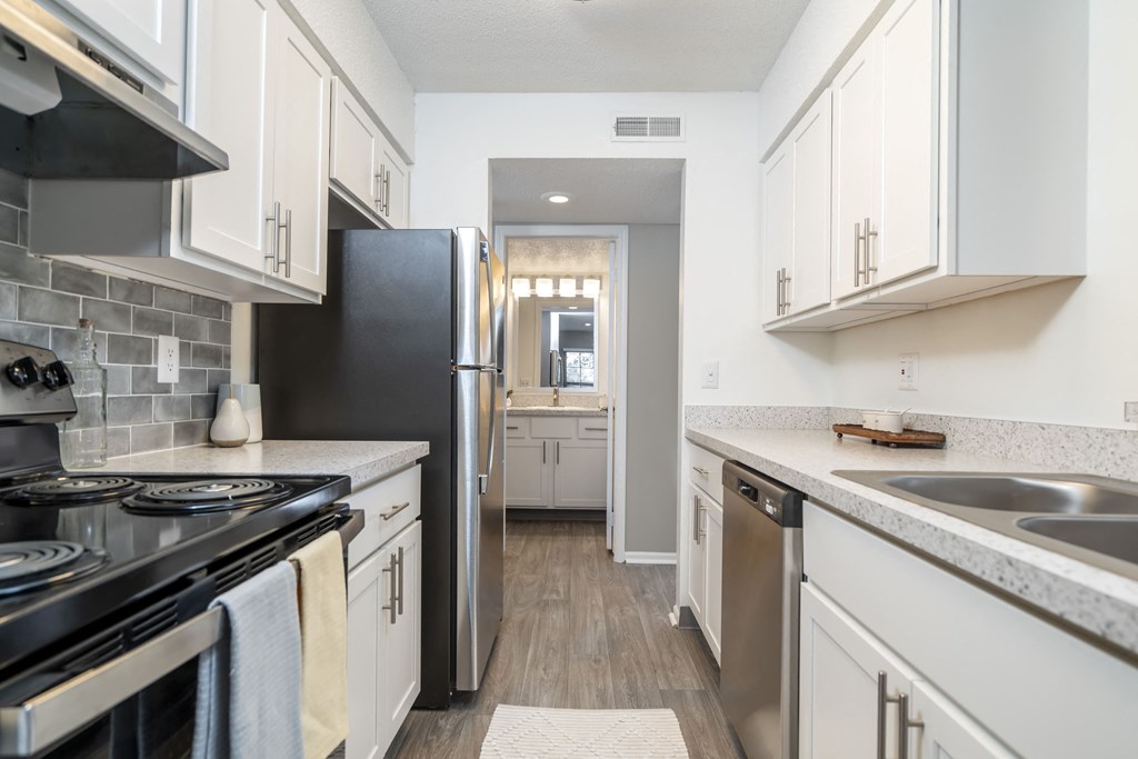 a kitchen with white cabinets and stainless steel appliances and a black refrigerator