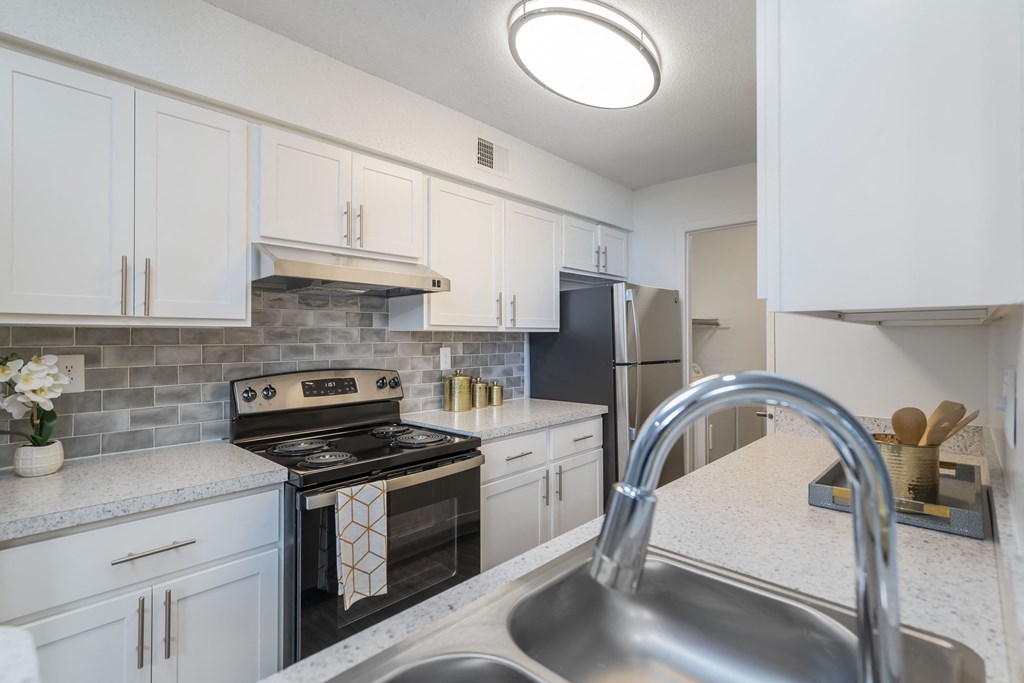 a kitchen with white cabinets and black appliances and a sink