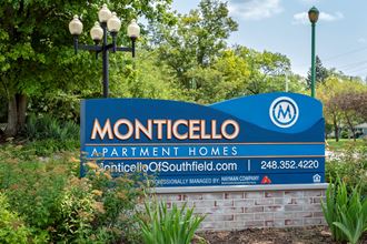 a sign for monticello apartment homes in front of a garden