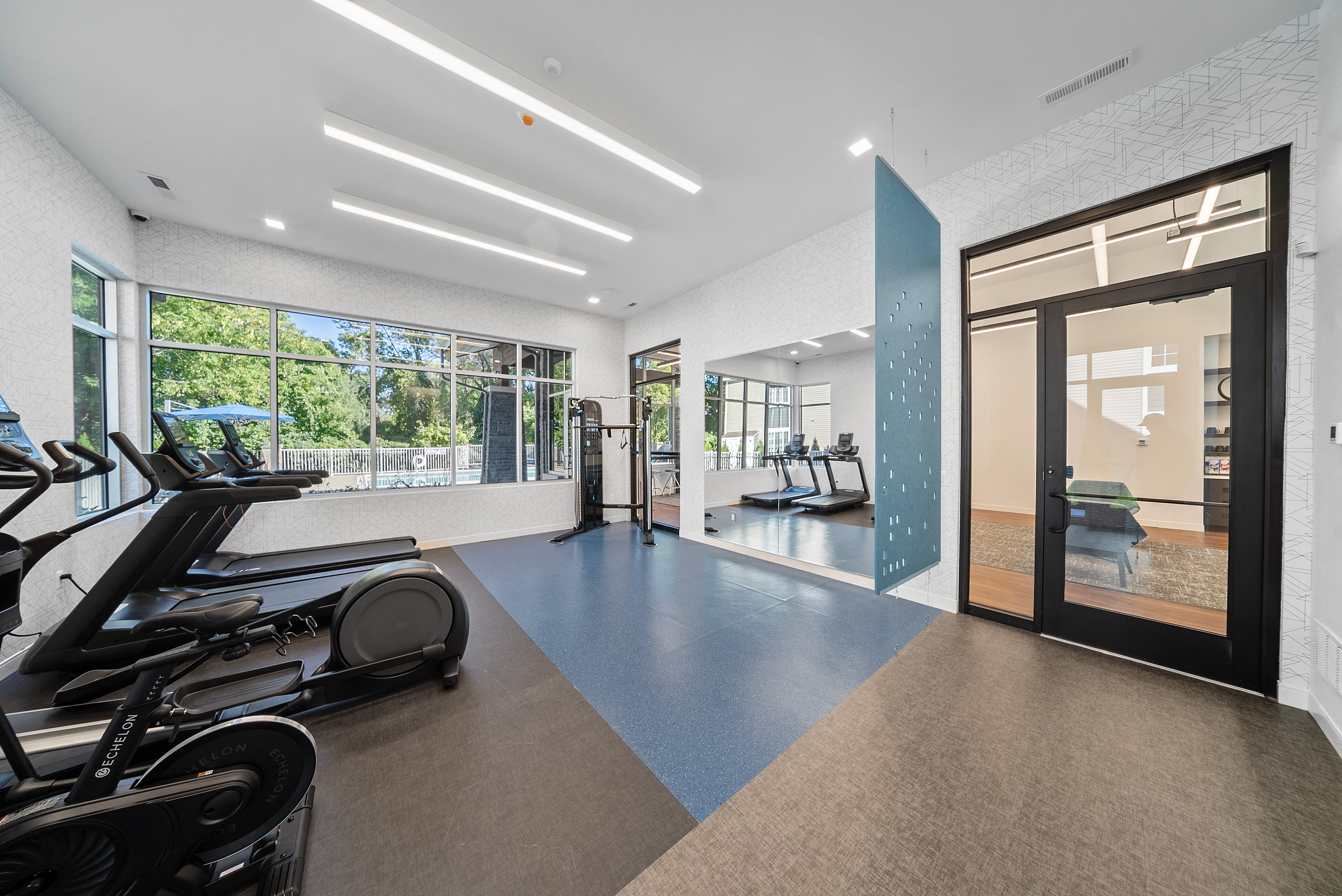 a gym with treadmills and glass doors and a view of a fitness center