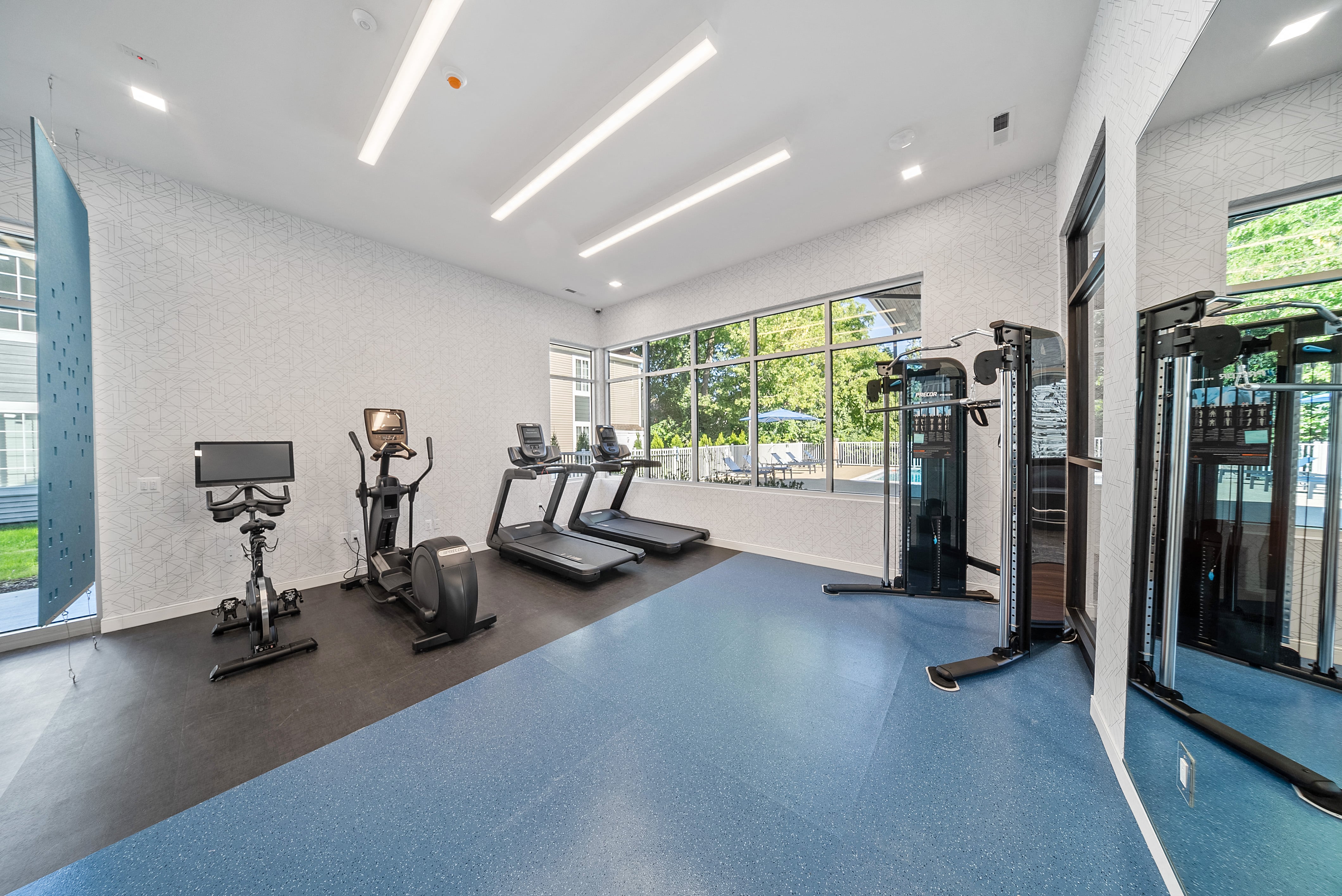 a gym with cardio machines and weights on a blue floor