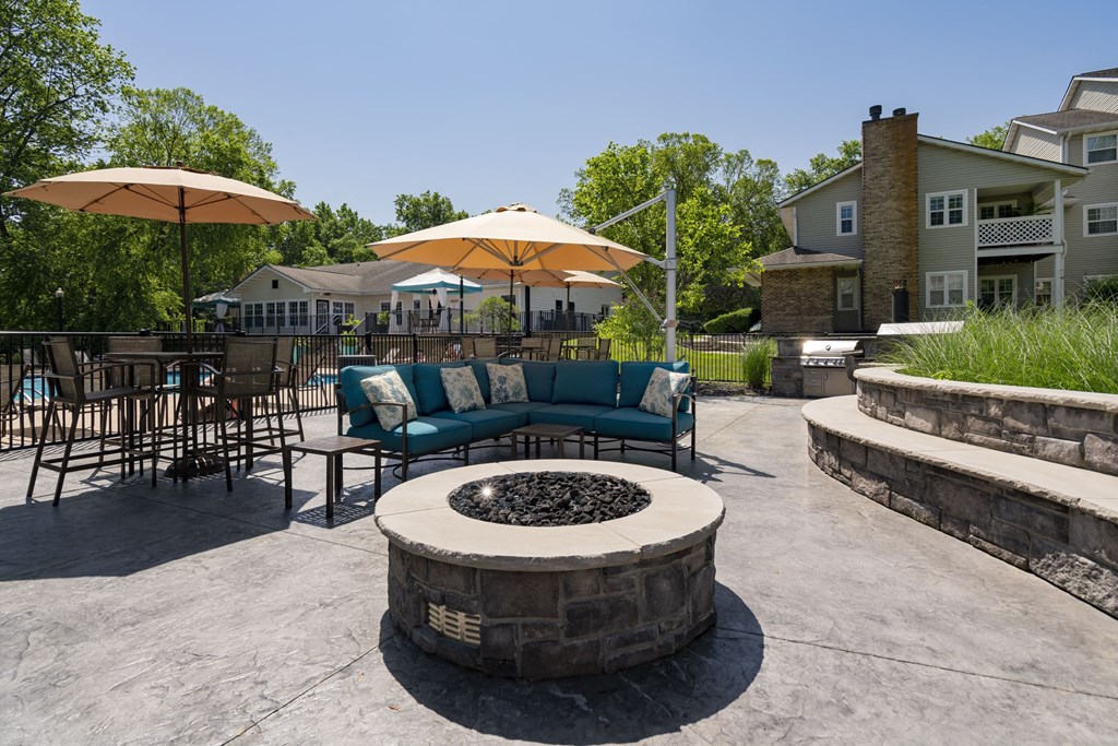 an outdoor patio with chairs and umbrellas and a fire pit