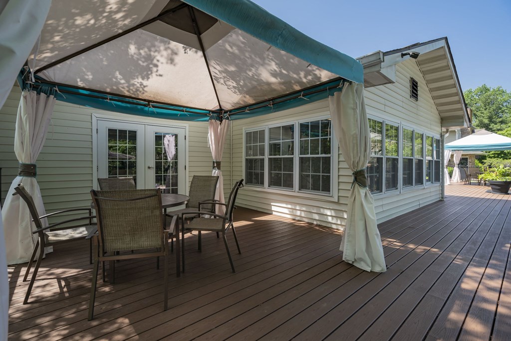 a covered patio with a table and chairs under an umbrella
