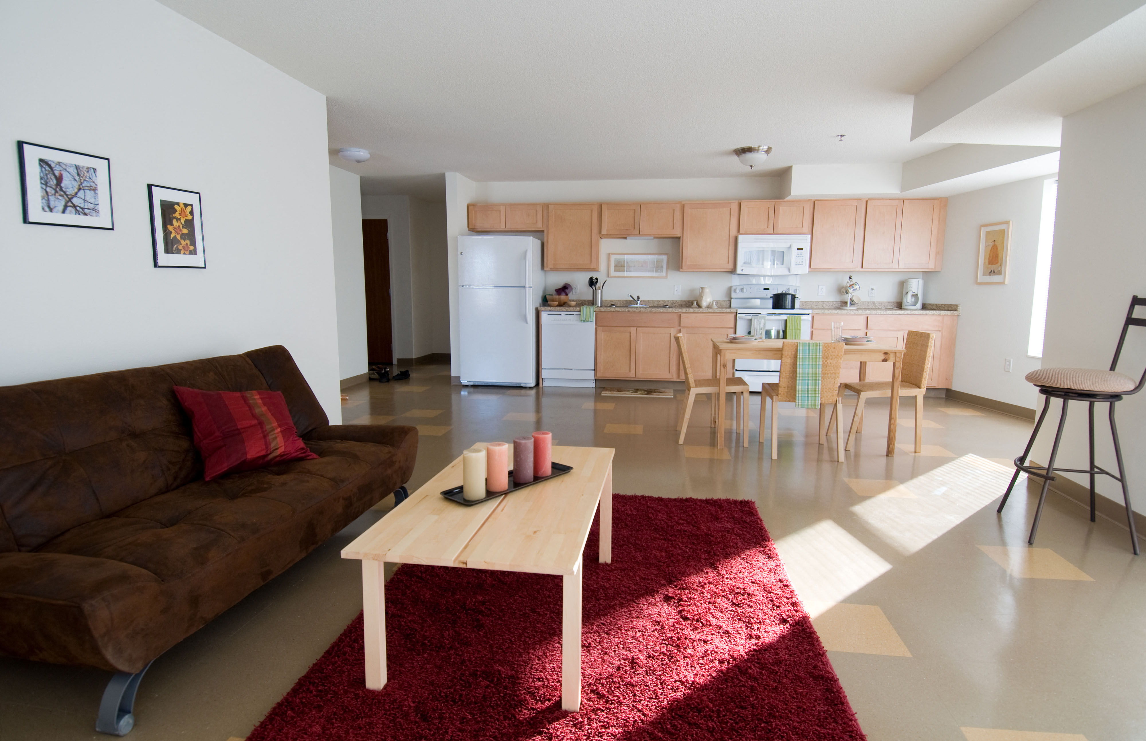 a living room with a couch and a table in front of a kitchen