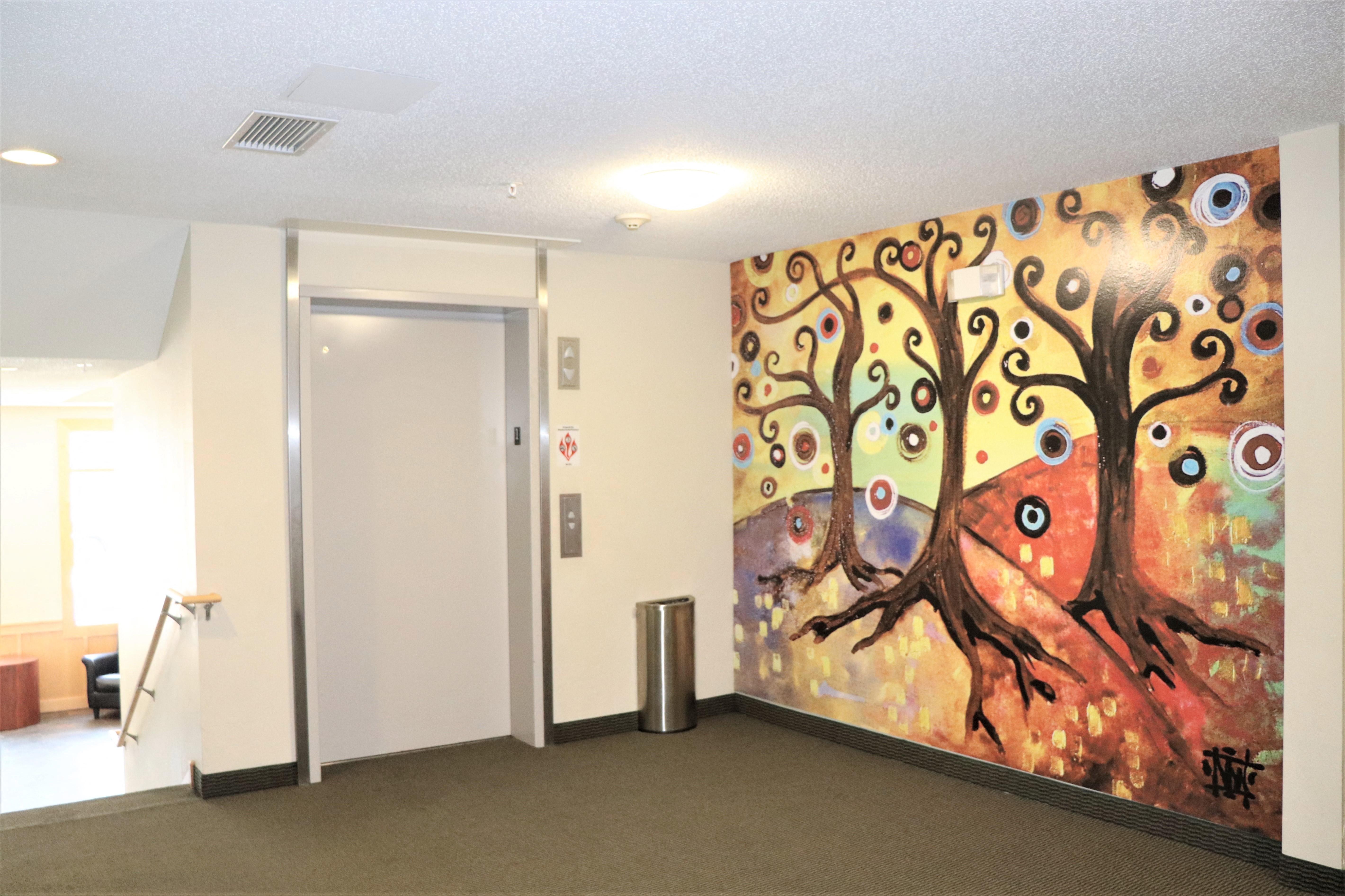 a painting of a tree with eyes on the wall in a hallway