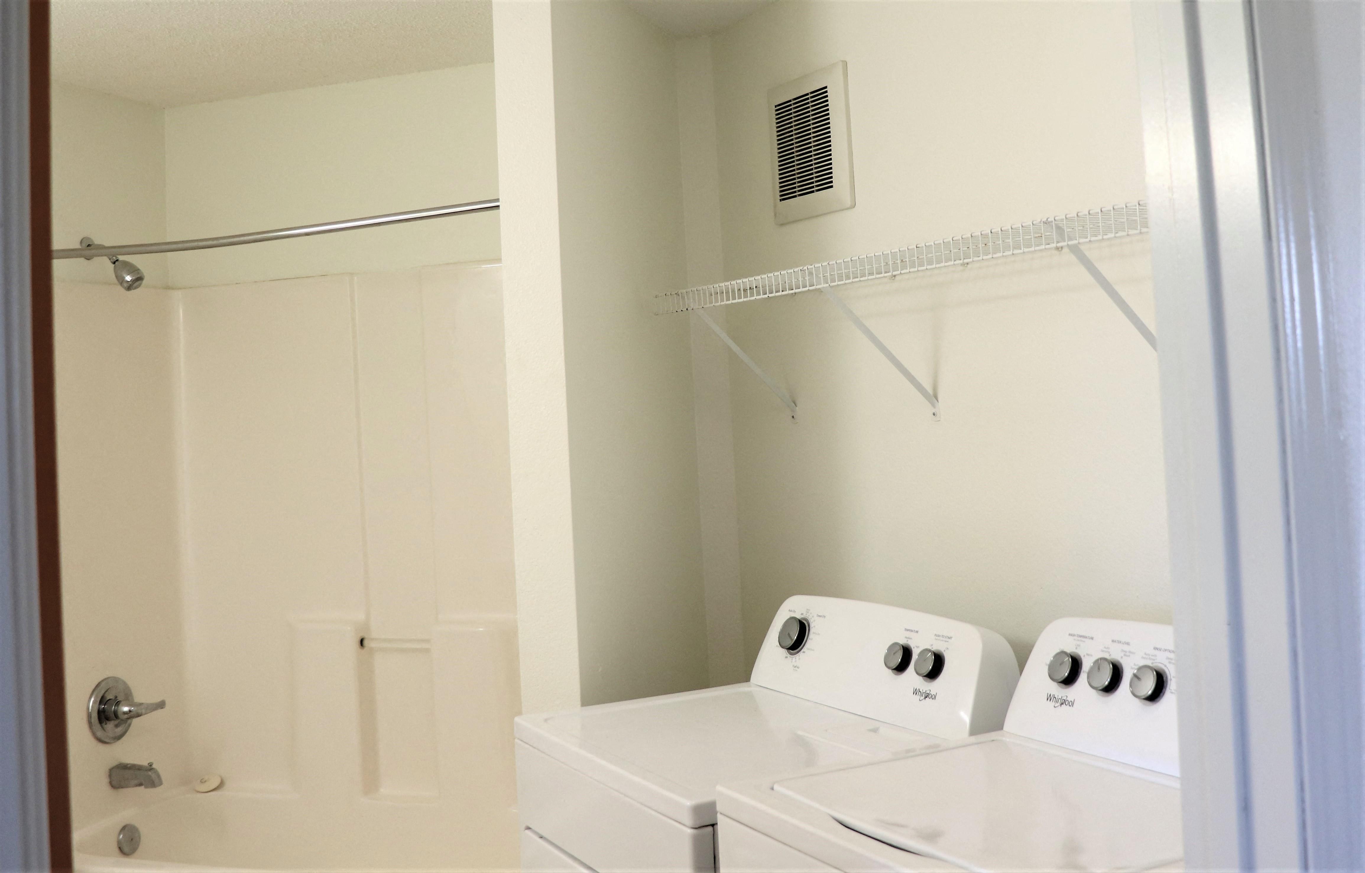 a white laundry room with two washers and a shower