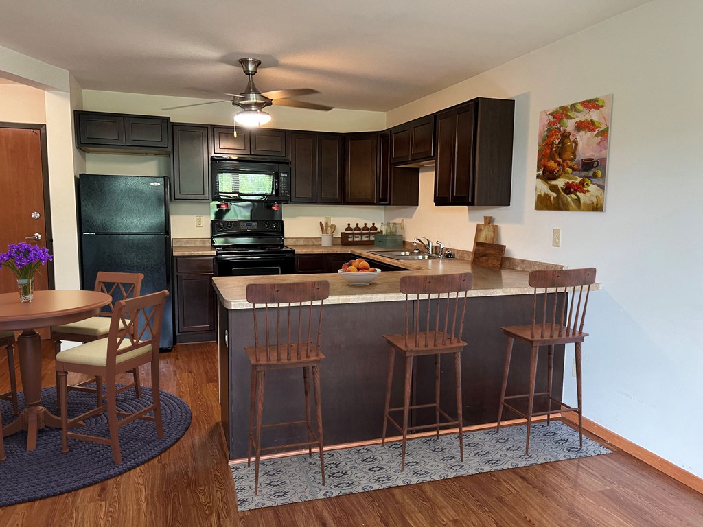 a kitchen with black appliances and a bar with stools