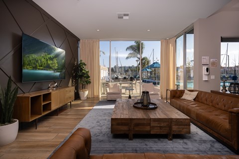 A modern living room with a large flat screen TV and a view of a marina.