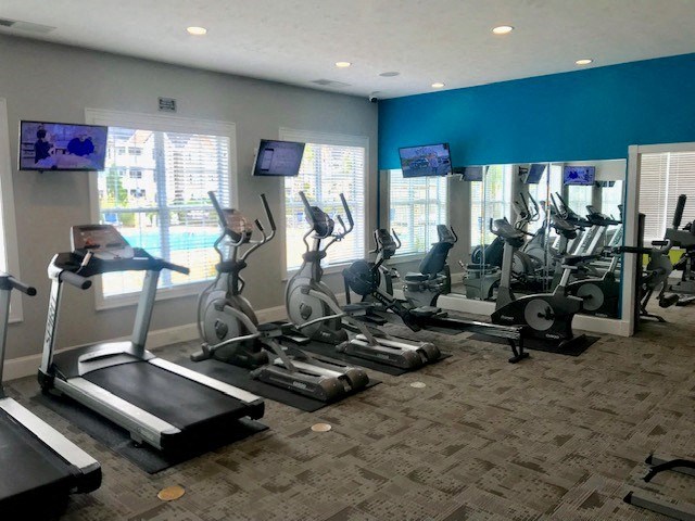 a gym with various exercise machines and televisions