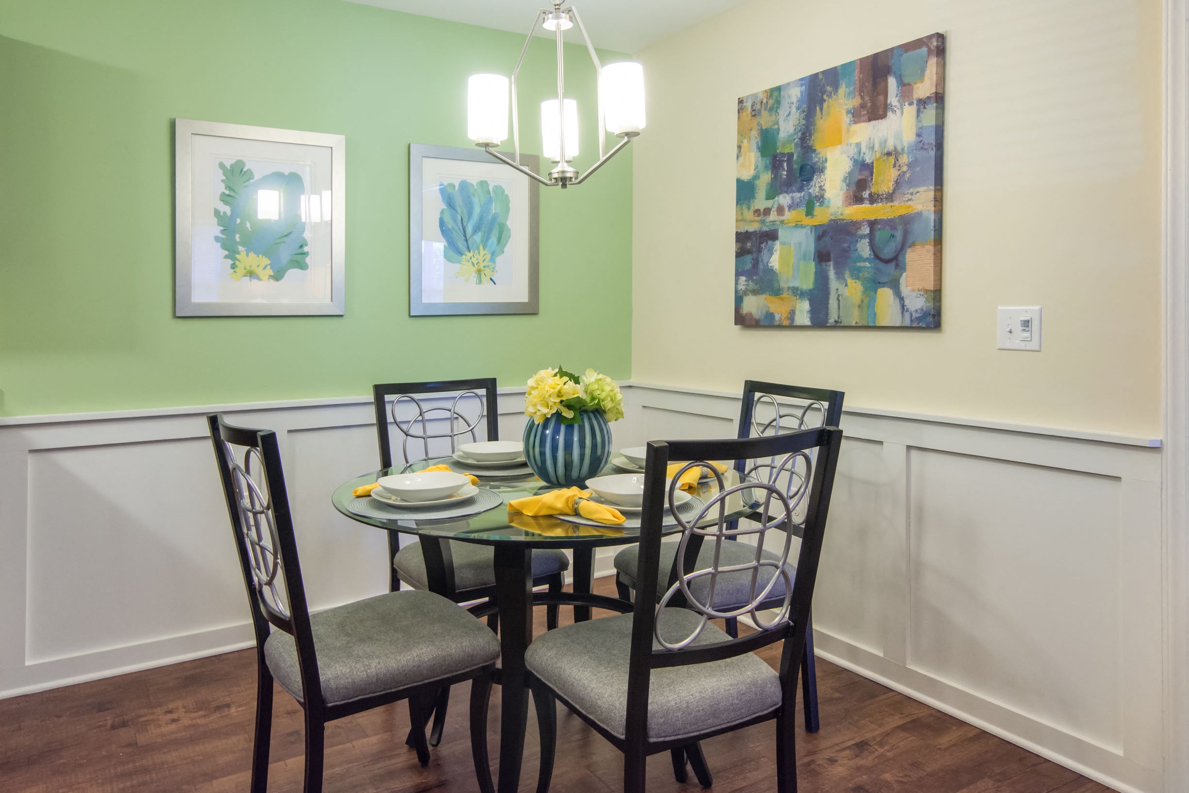 a dining room with a table and chairs and paintings on the wall