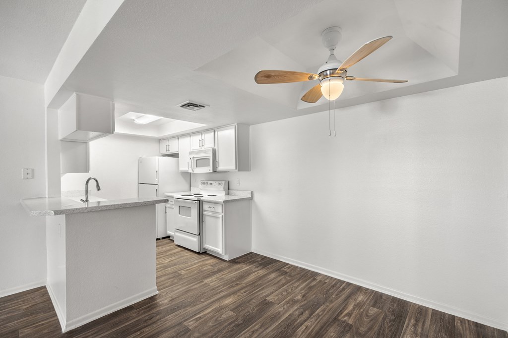 the living room and kitchen of an apartment with a ceiling fan the living room and kitchen of an apartment with a ceiling fan