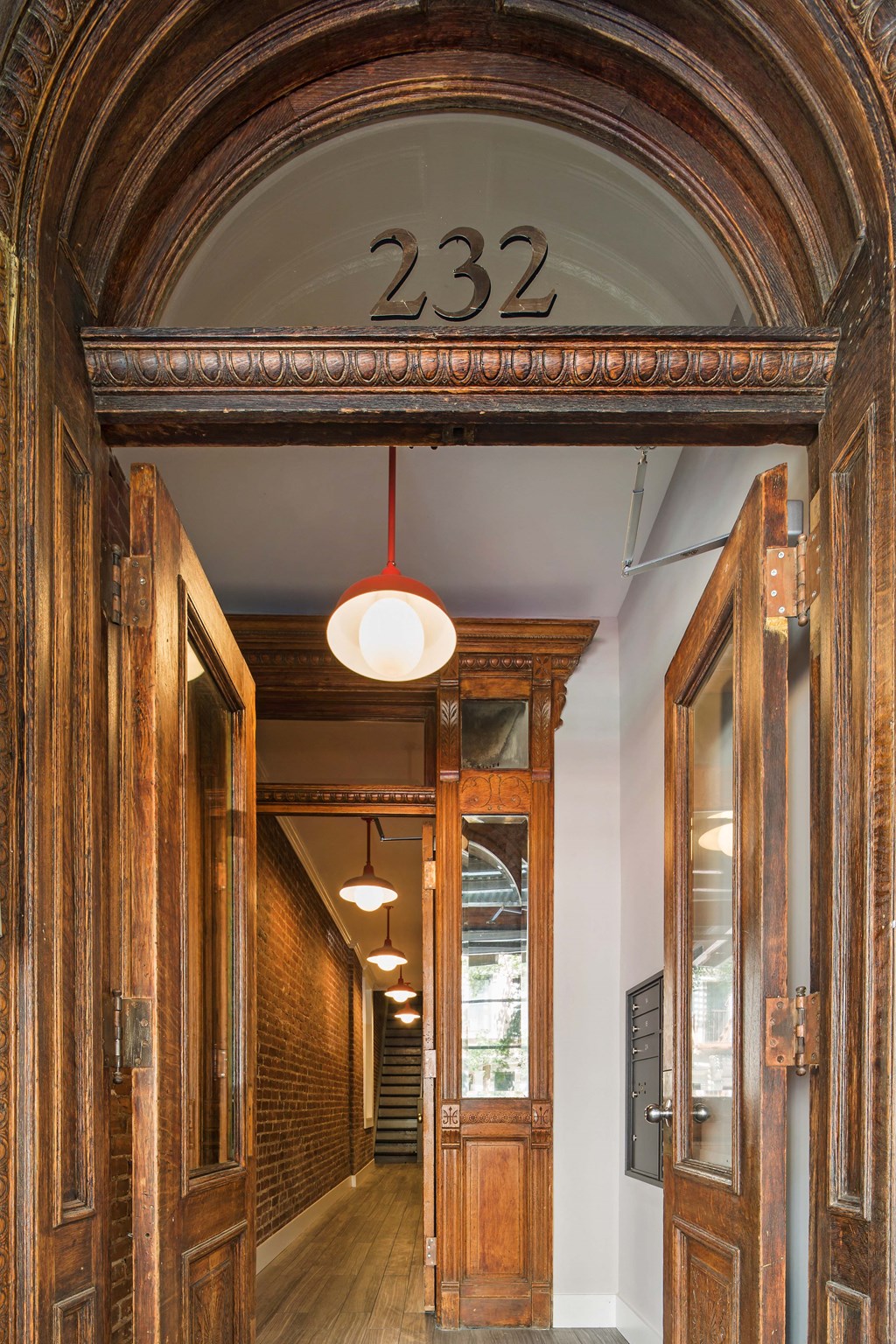 the entrance to a hallway with wooden doors and a red light hanging from the ceiling