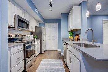 White kitchen cabinetry, quartz surfaces, and stainless steel appliances at Sunscape Apartments, near Carilion Hospital, VA