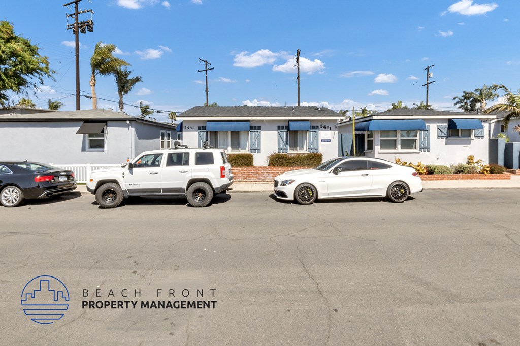 two white cars parked in a parking lot in front of houses