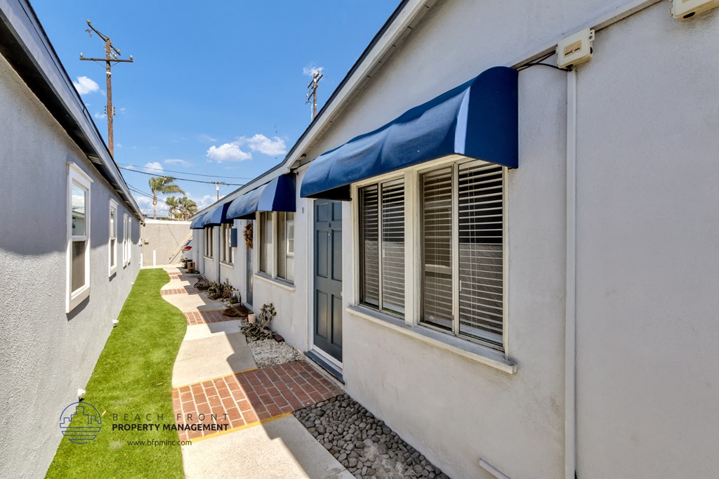 a side view of a white building with blue awnings and a sidewalk