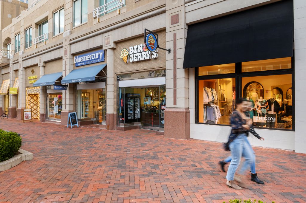 a man walks past the entrance to a store on a brick sidewalk