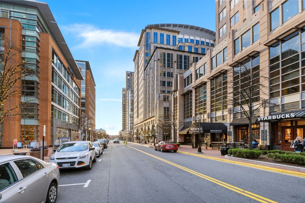 a city street with cars parked on the side of the road and tall buildings on either side