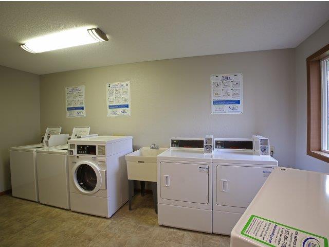 a laundry room with four washing machines and other appliances