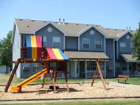a swing set in front of a blue house