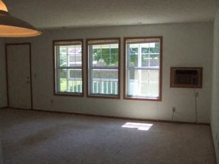 an empty living room with three windows in it