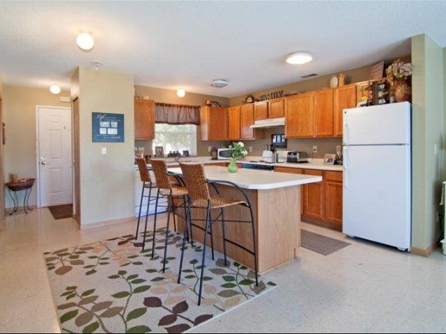 a kitchen with a white refrigerator and a bar with chairs