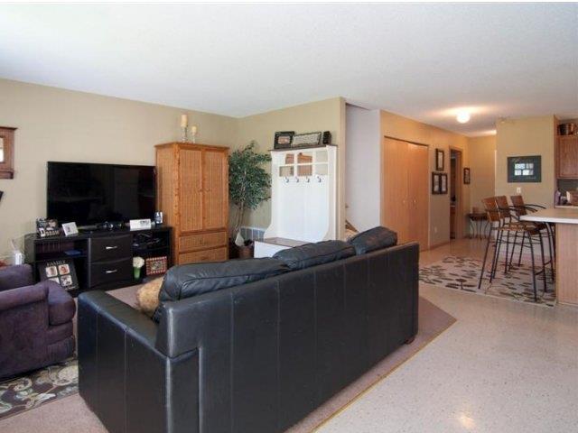 a living room with a black couch and a kitchen