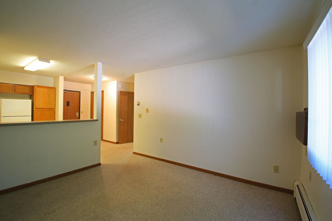an empty living room and kitchen with a white wall