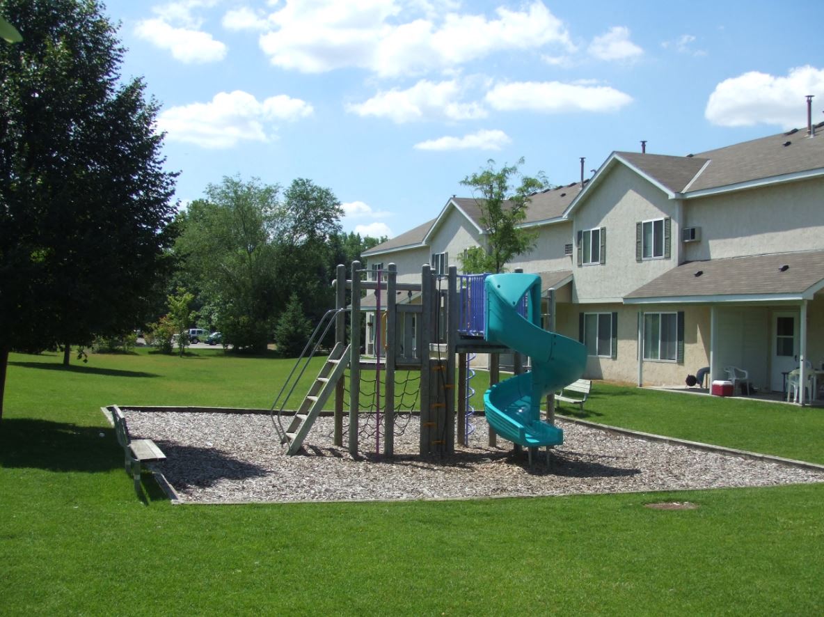 a playground with a slide in front of a house