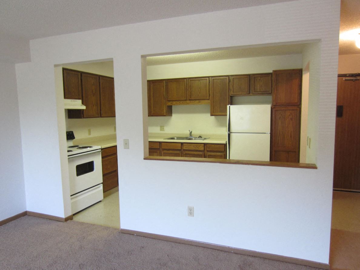 an empty kitchen with white appliances and wooden cabinets
