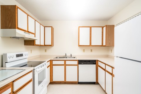 A kitchen with white appliances and wooden cabinets.