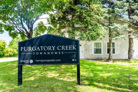 A sign for Purgatory Creek Townhomes stands in front of a house.