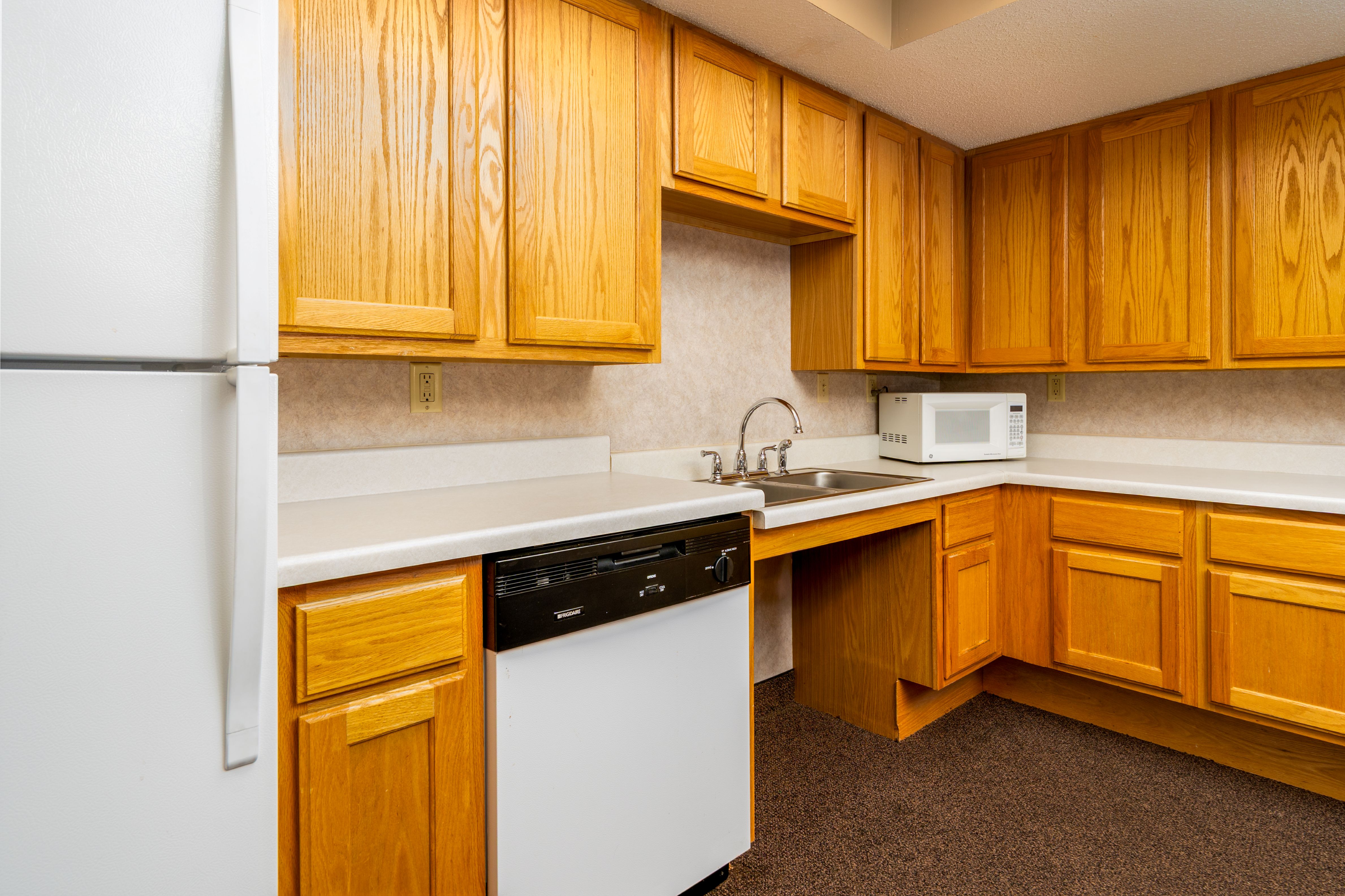 A kitchen with wooden cabinets and a white refrigerator.