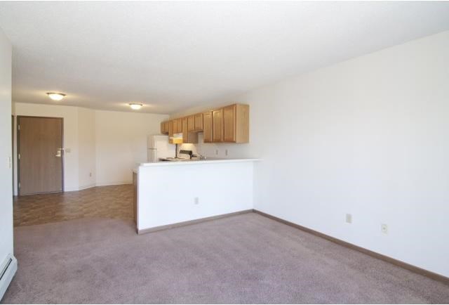 an empty living room and kitchen with white walls