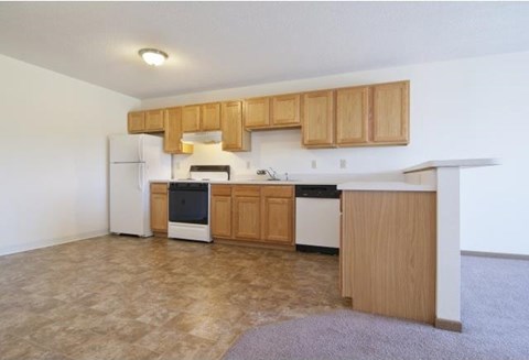 an empty kitchen with wood cabinets and white appliances