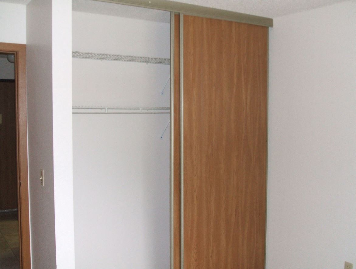 a closet with a wooden door and a white wall